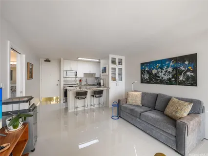 a living room with furniture a rug and kitchen view