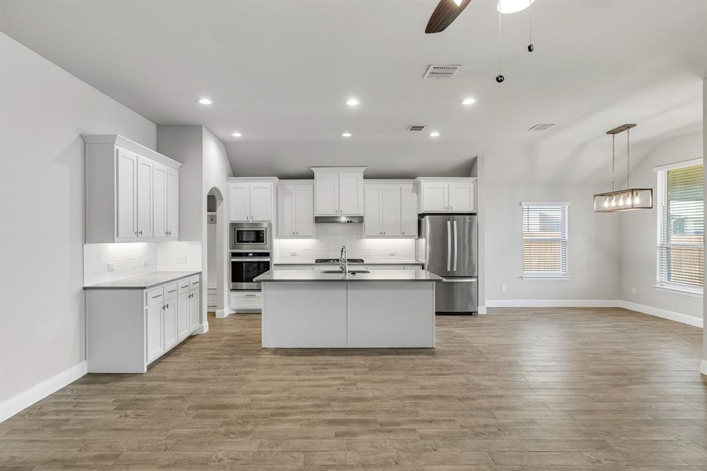 915 Timber Ridge Drive Justin, TX 76247 - Photo 7 of 39 Contemporary kitchen featuring white cabinetry, a center island, stainless steel appliances, and wood-finish flooring