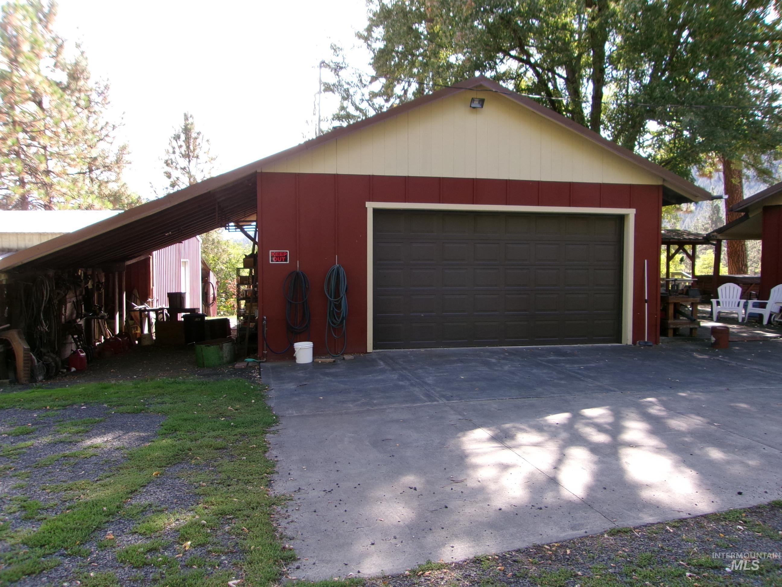 307 Locust Road Kamiah, ID 83536 - Photo 8 of 50 Attached garage with a dark brown overhead door, extended covered carport, and concrete driveway