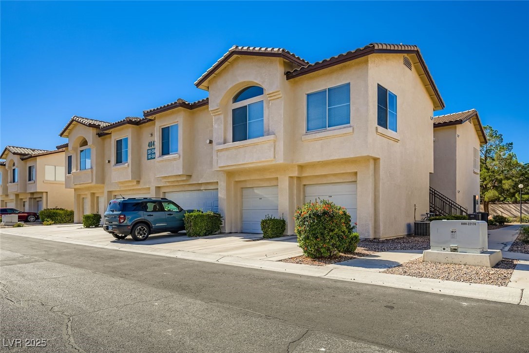 Mediterranean / spanish home featuring an attached garage, a residential view, stucco siding, driveway, and a tile roof