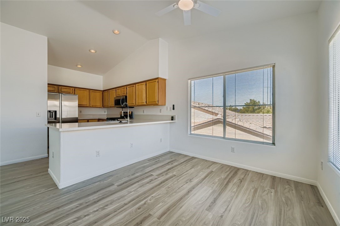 4941 Black Bear Road, Unit 203 Las Vegas, NV 89149 - Photo 3 of 11 Kitchen featuring light countertops, light wood-style floors, appliances with stainless steel finishes, a peninsula, and brown cabinets
