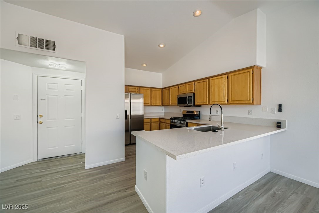 4941 Black Bear Road, Unit 203 Las Vegas, NV 89149 - Photo 4 of 11 Kitchen with a peninsula, stainless steel appliances, light wood-style floors, recessed lighting, and light stone countertops