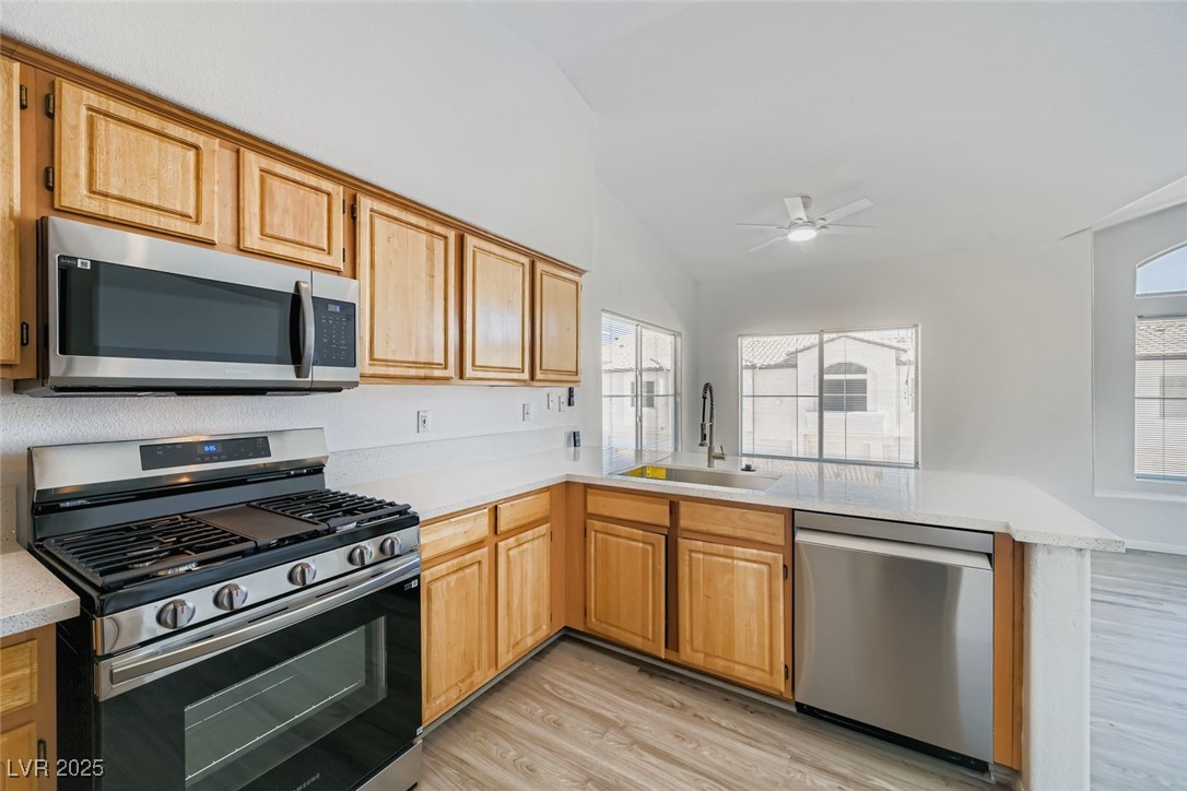 4941 Black Bear Road, Unit 203 Las Vegas, NV 89149 - Photo 5 of 11 Kitchen featuring appliances with stainless steel finishes, light wood-style flooring, light brown cabinetry, a ceiling fan, and vaulted ceiling