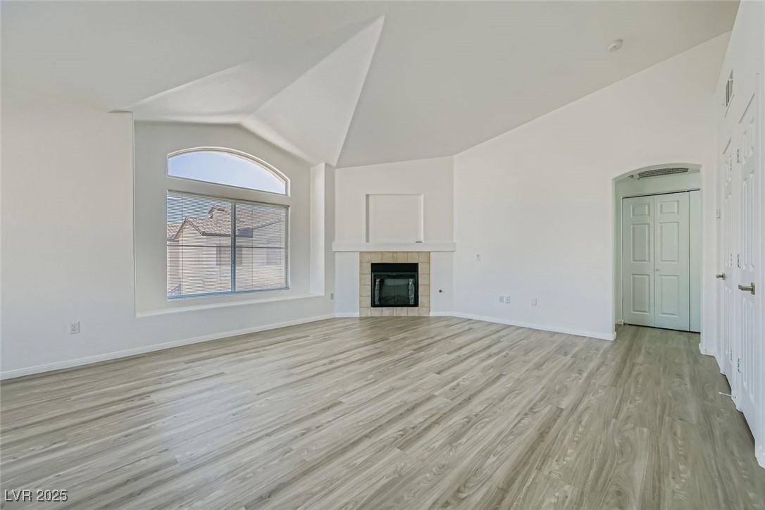 4941 Black Bear Road, Unit 203 Las Vegas, NV 89149 - Photo 6 of 11 Unfurnished living room featuring light wood-style flooring, a fireplace, and high vaulted ceiling