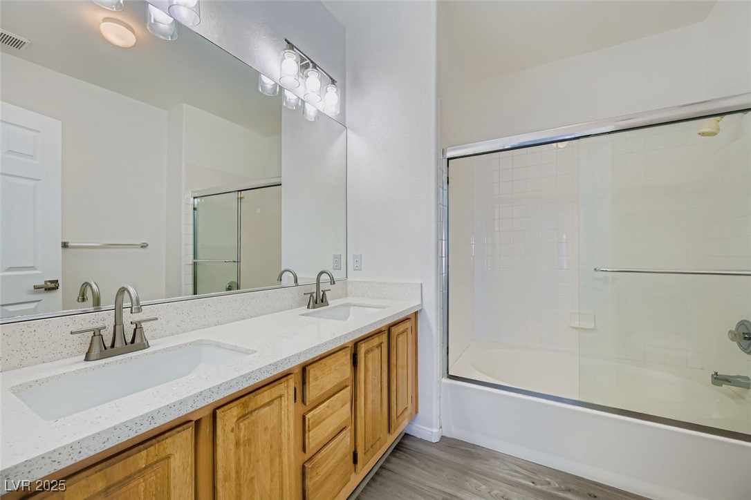 4941 Black Bear Road, Unit 203 Las Vegas, NV 89149 - Photo 8 of 11 Full bathroom with double vanity, light wood-style flooring, and combined bath / shower with glass door