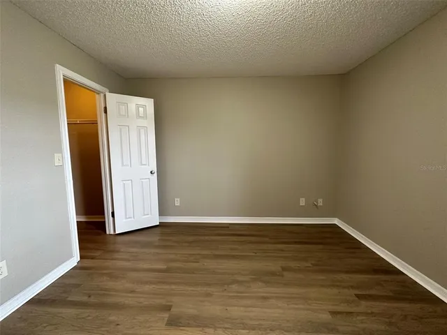 a view of an empty room with wooden floor and closet