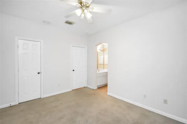 an empty room with a chandelier fan and windows