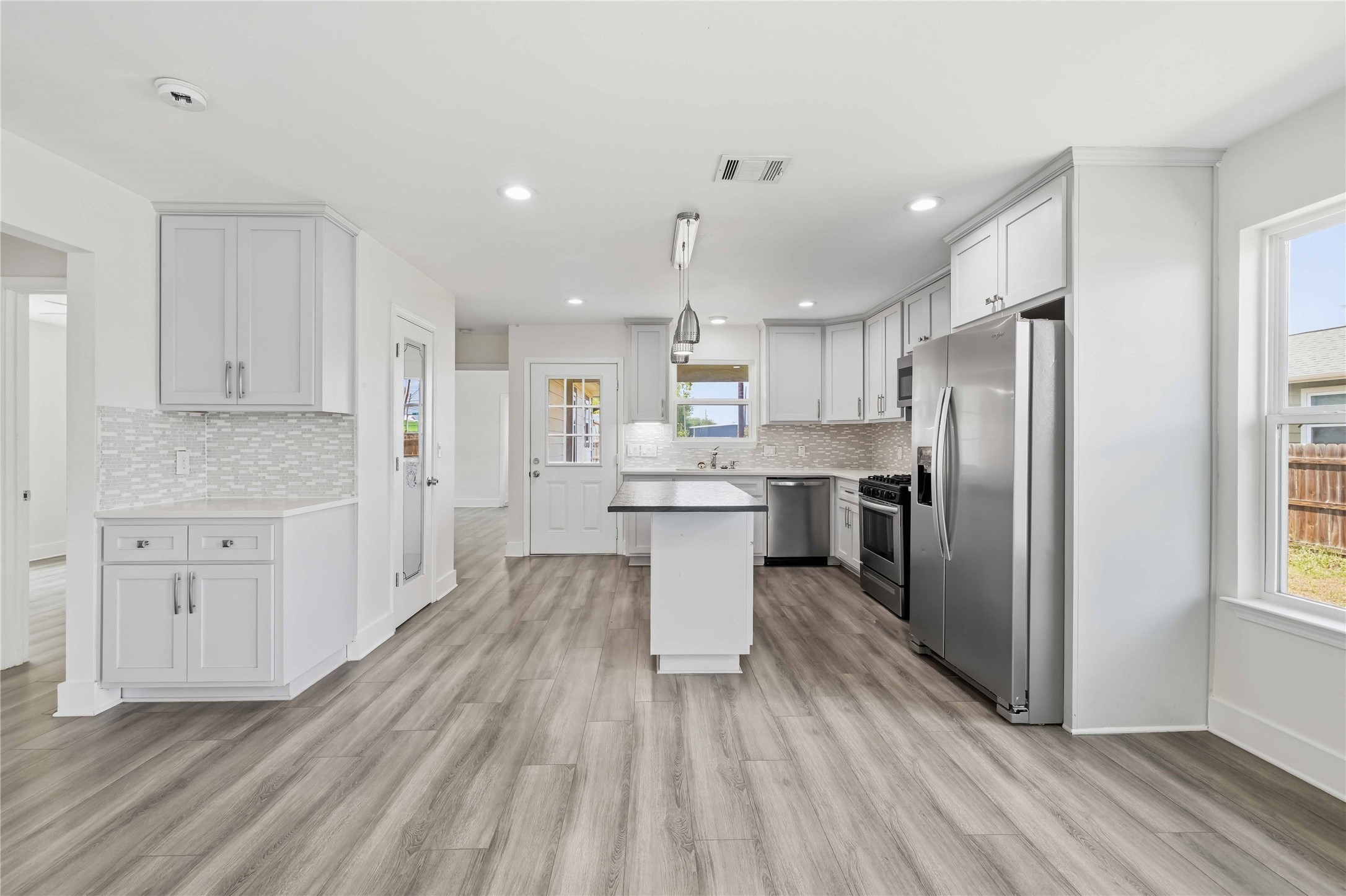 400 Booth Street Taylor, TX 76574 - Photo 11 of 35 Kitchen featuring stainless steel appliances, a kitchen island, decorative backsplash, and light wood-style floors