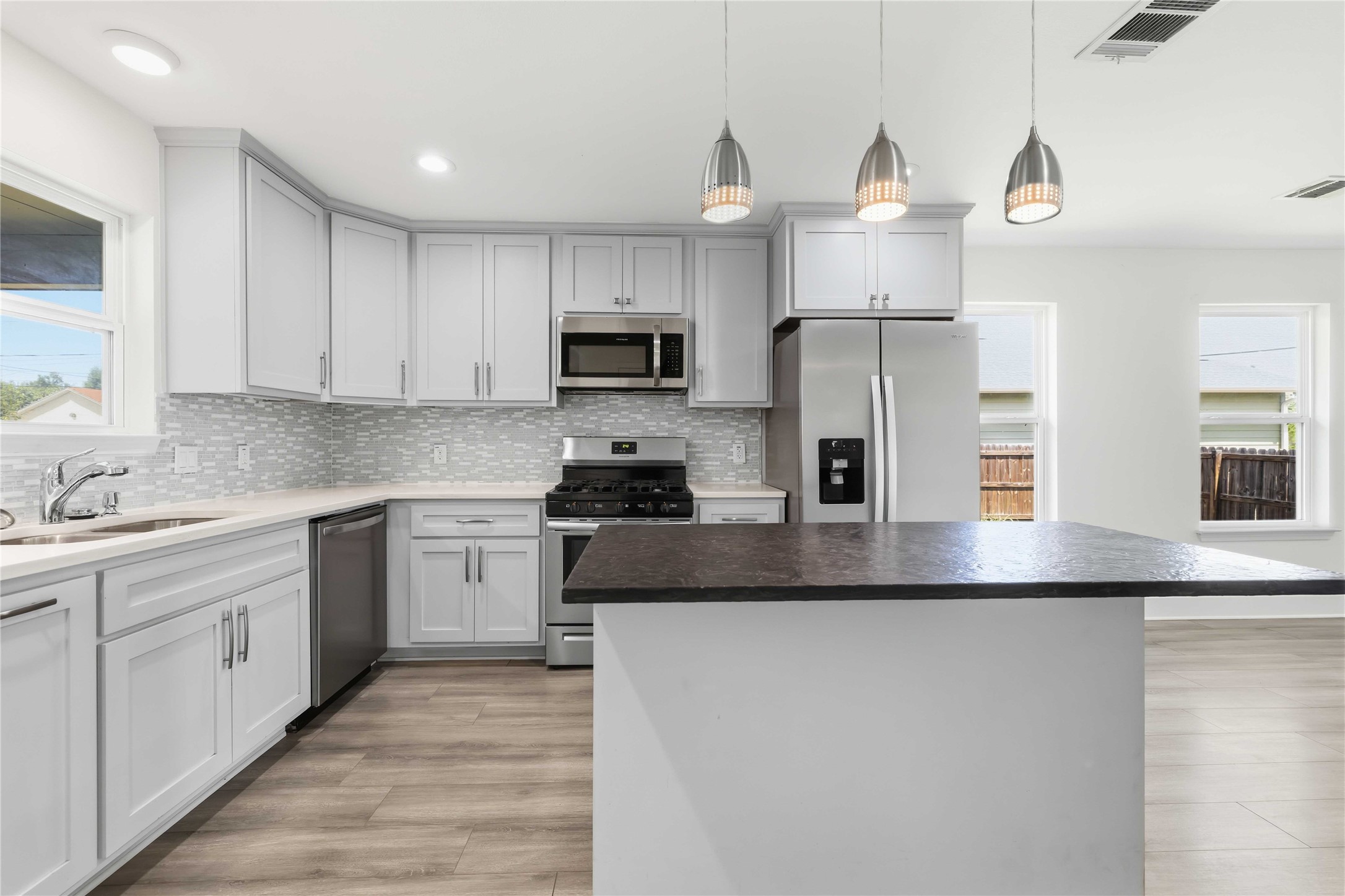 400 Booth Street Taylor, TX 76574 - Photo 15 of 35 Kitchen featuring stainless steel appliances, a center island, light wood-style floors, pendant lighting, and decorative backsplash