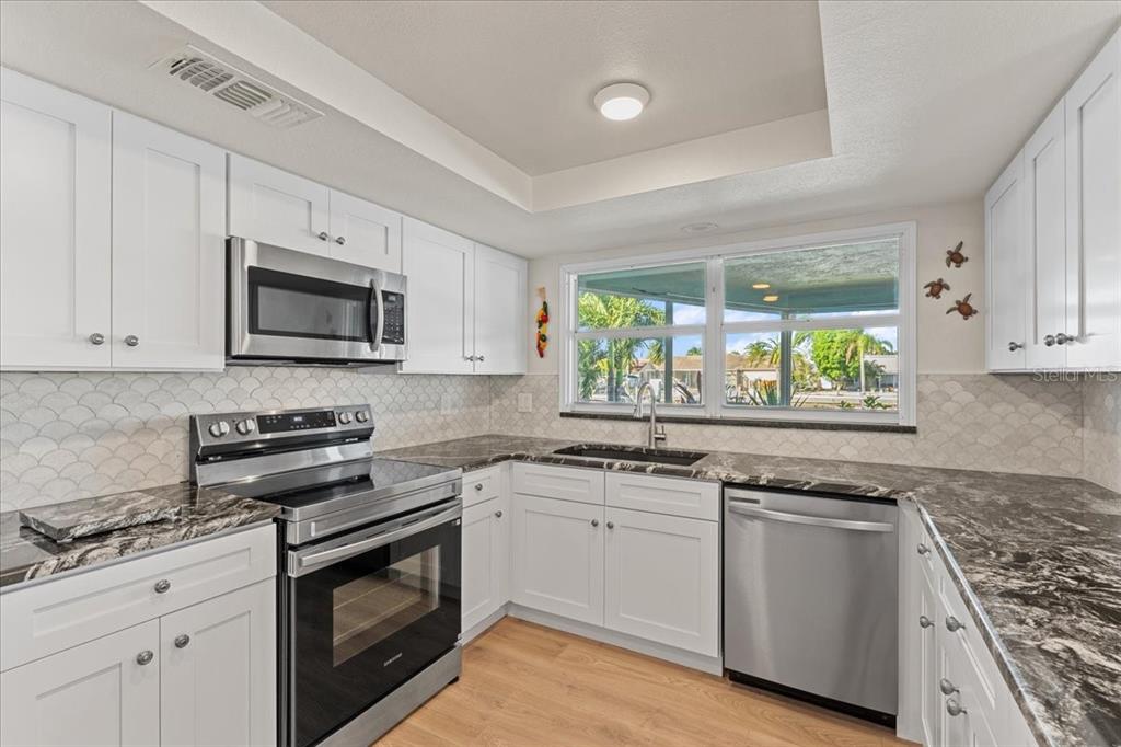 5028 Ensign Loop New Port Richey, FL 34652 - Photo 18 of 76 a kitchen with white cabinets appliances and a window