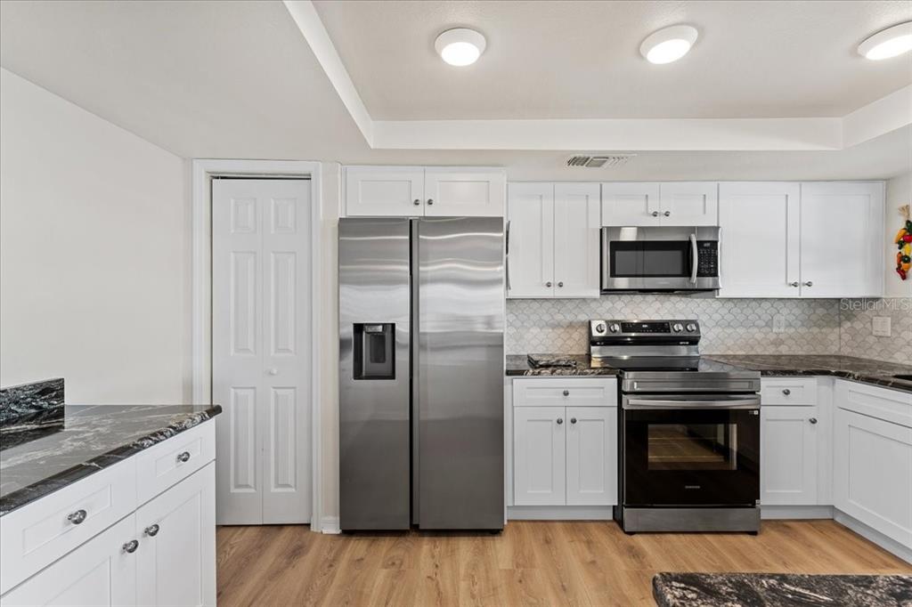 5028 Ensign Loop New Port Richey, FL 34652 - Photo 19 of 76 a kitchen with stainless steel appliances granite countertop a stove a refrigerator and a microwave