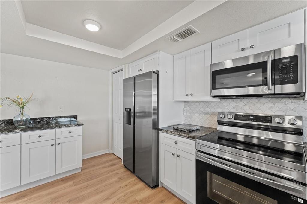 5028 Ensign Loop New Port Richey, FL 34652 - Photo 21 of 76 a kitchen with stainless steel appliances a stove a microwave and cabinets