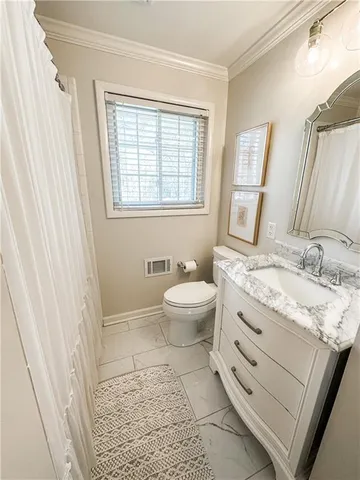 a bathroom with a granite countertop sink toilet a mirror and a window