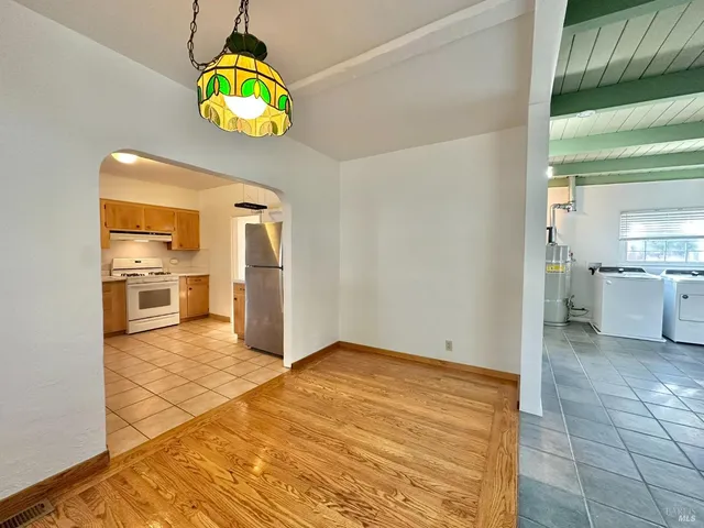 an empty room with wooden floor chandelier fan and windows