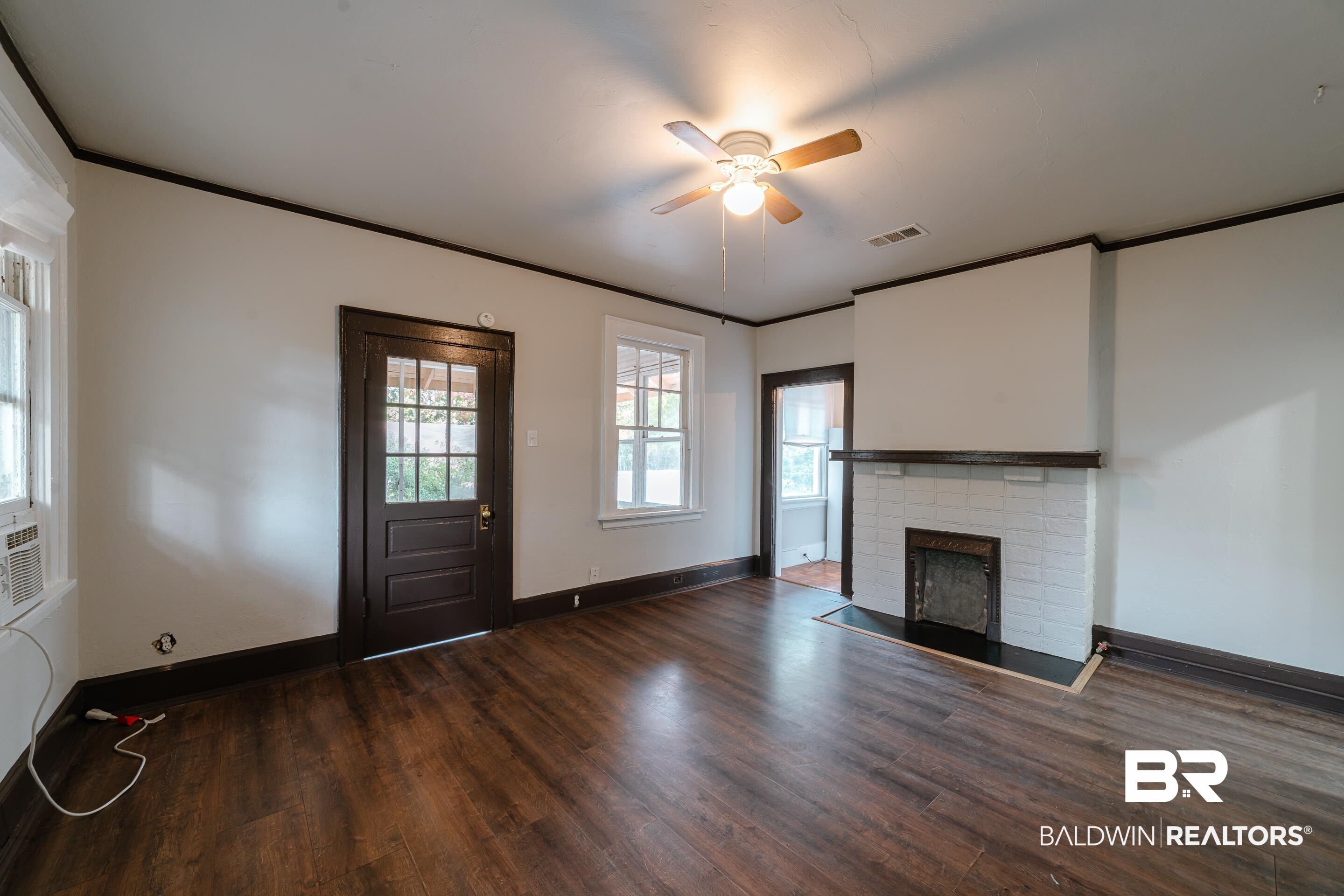 312 1st Street Mobile, AL 36611 - Photo 7 of 29 Unfurnished living room with crown molding, ceiling fan, a fireplace, and dark hardwood / wood-style flooring