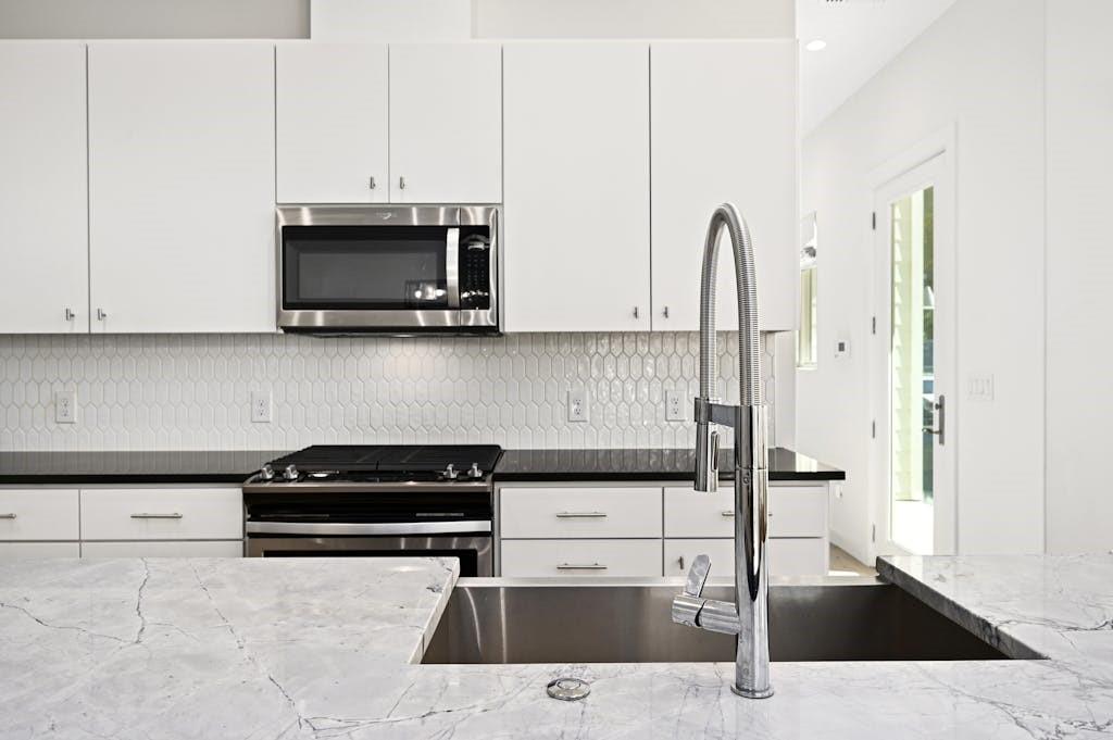 5212 Huisache Street, Unit 2 Austin, TX 78751 - Photo 12 of 30 Kitchen featuring white cabinetry, stainless steel appliances, dark stone counters, and backsplash