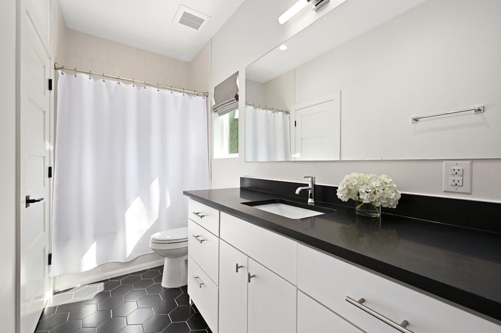 5212 Huisache Street, Unit 2 Austin, TX 78751 - Photo 26 of 30 Bathroom featuring vanity, shower / bath combination with curtain, and dark tile patterned flooring