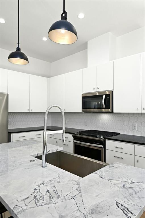 5212 Huisache Street, Unit 2 Austin, TX 78751 - Photo 9 of 30 Kitchen with dark stone counters, stainless steel appliances, hanging light fixtures, and white cabinetry