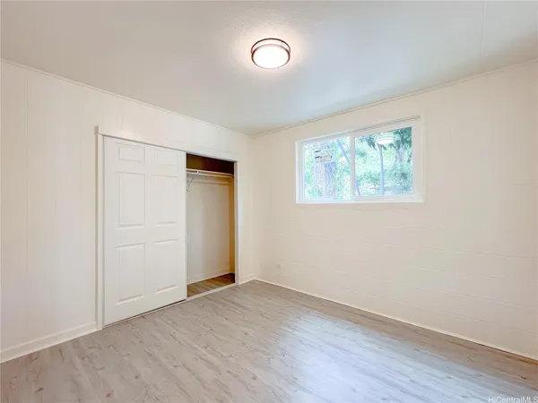 an empty room with wooden floor cabinet and windows