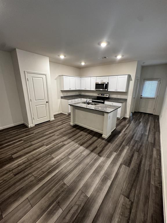 1813 Chapel Hill Road Princeton, TX 75407 - Photo 5 of 20 Open-concept kitchen with wood-finish flooring, white cabinetry, a central island, stainless steel appliances, and recessed lighting