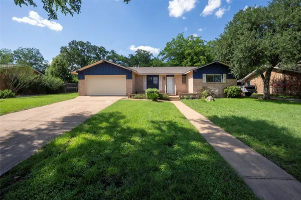 a front view of a house with a yard and trees
