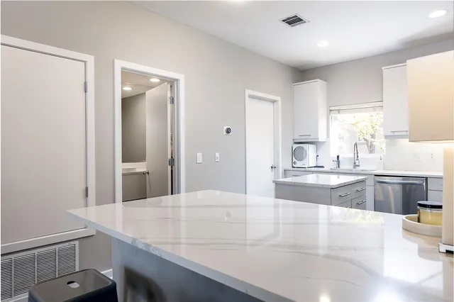 a large kitchen with kitchen island a sink dishwasher a stove and white cabinets with wooden floor