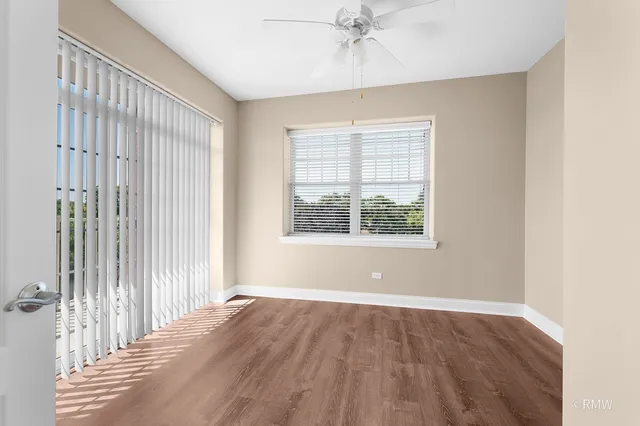 an empty room with wooden floor fan and windows