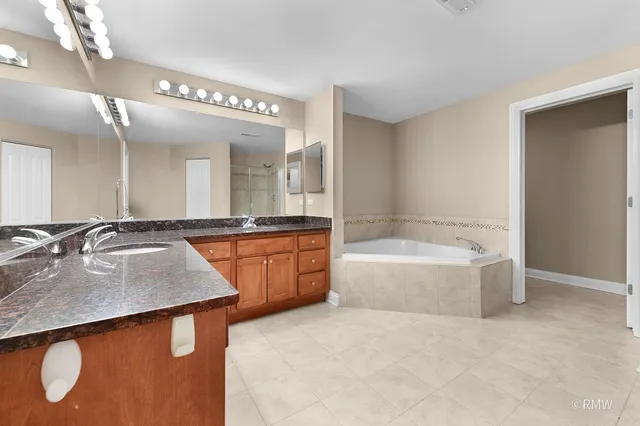 a bathroom with a granite countertop sink a bathtub a mirror and a vanity