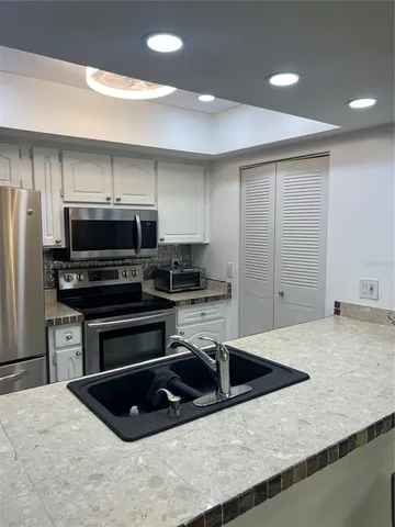 a kitchen with stainless steel appliances a stove a sink a microwave a refrigerator and cabinets