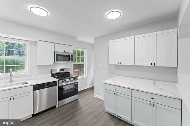 a kitchen with granite countertop white cabinets and appliances