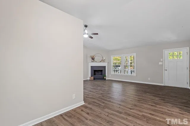 a view of an empty room with a window and fireplace