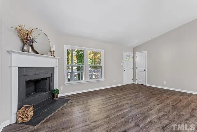 a view of an empty room with a fireplace and a window
