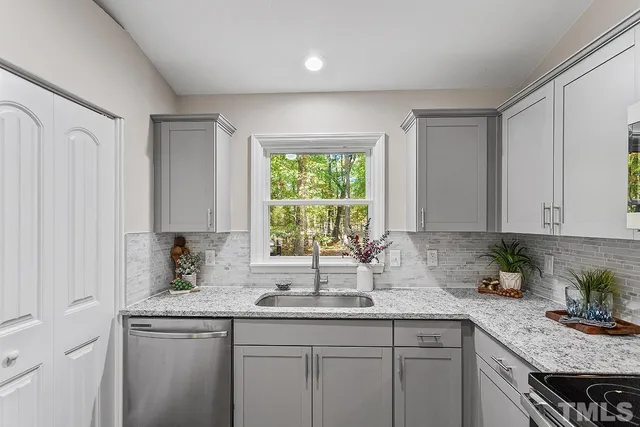 a kitchen with stainless steel appliances granite countertop a sink a window and cabinets