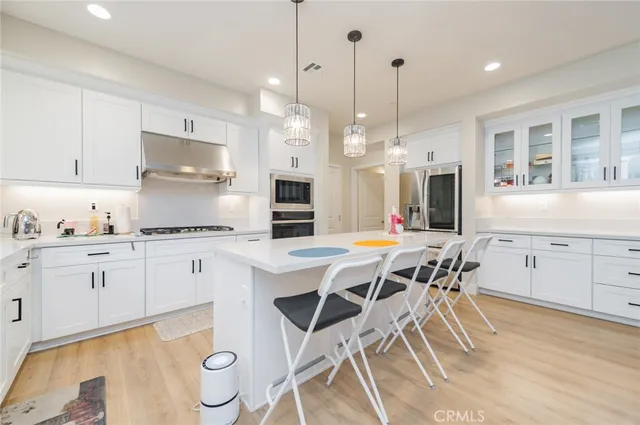 a kitchen with stainless steel appliances kitchen island granite countertop a table chairs sink and cabinets