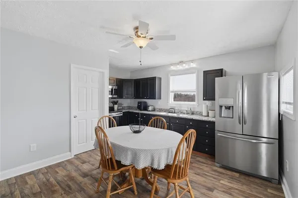 a kitchen with stainless steel appliances a dining table chairs and refrigerator