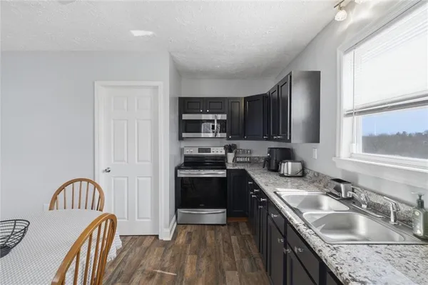 a kitchen with granite countertop a sink stainless steel appliances and cabinets