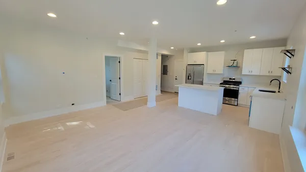 a view of a kitchen with a sink and dishwasher a refrigerator with white cabinets