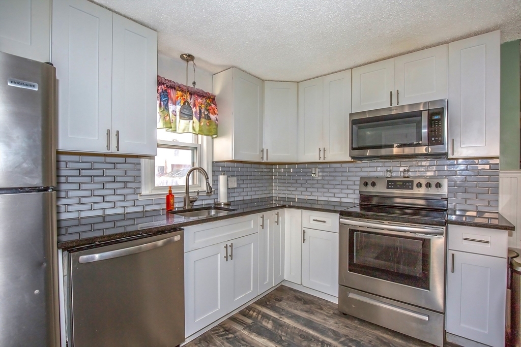 65 Garland Street Springfield, MA 01118 - Photo 11 of 39 a kitchen with stainless steel appliances granite countertop a sink stove a microwave and cabinets