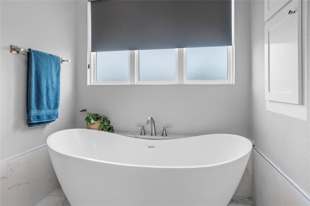 1024 Henry Way Springtown, TX 76082 - Photo 17 of 29 Freestanding soaking tub with brushed nickel fixtures, set against a window with privacy glass and a dark roller shade
