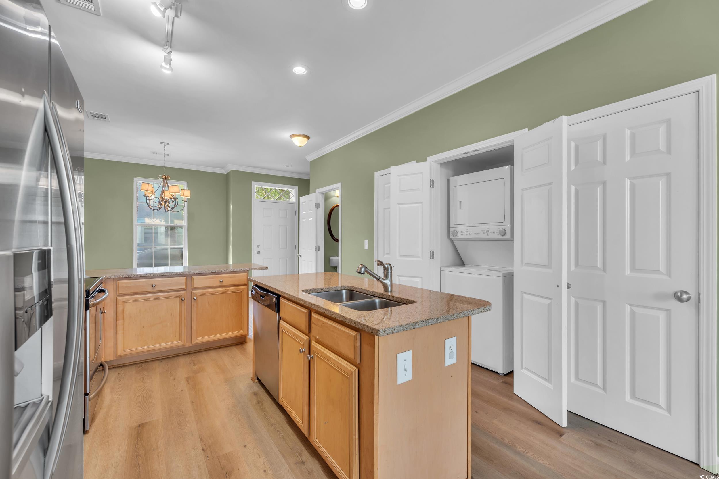 945 Rosencrans Lane, Unit B Myrtle Beach, SC 29577 - Photo 11 of 32 Kitchen with stacked washing machine and dryer, stainless steel appliances, light wood finished floors, a chandelier, and a center island with sink