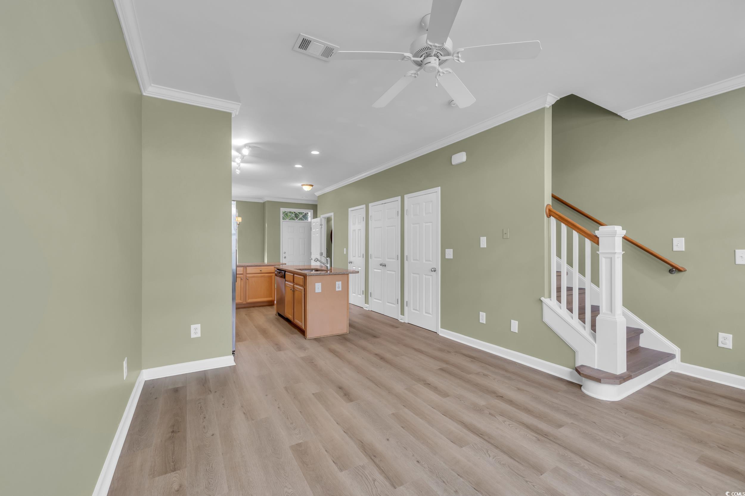 945 Rosencrans Lane, Unit B Myrtle Beach, SC 29577 - Photo 12 of 32 Unfurnished living room with crown molding, light wood-style floors, ceiling fan, and stairway