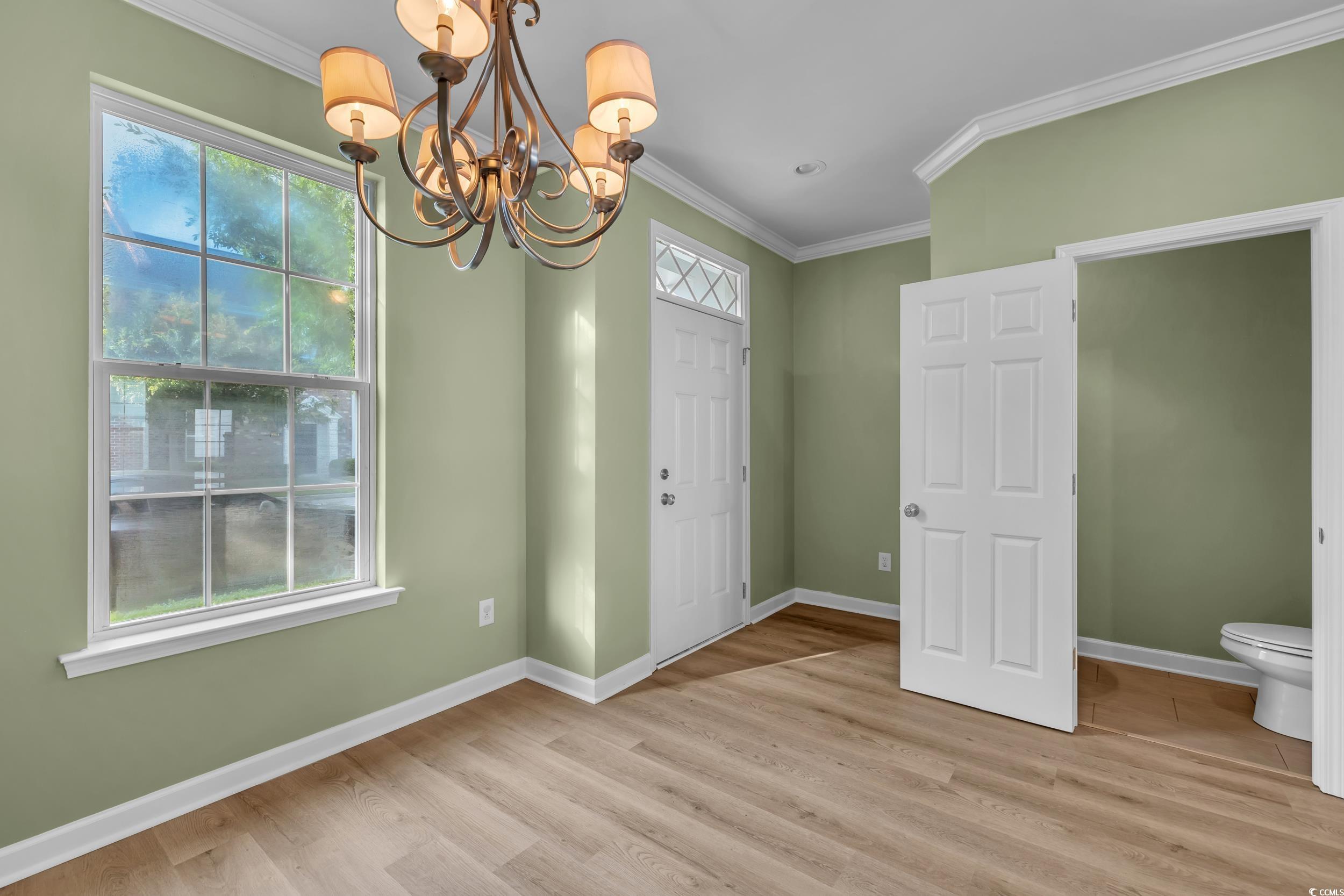945 Rosencrans Lane, Unit B Myrtle Beach, SC 29577 - Photo 3 of 32 Unfurnished dining area featuring a chandelier, crown molding, and light wood finished floors