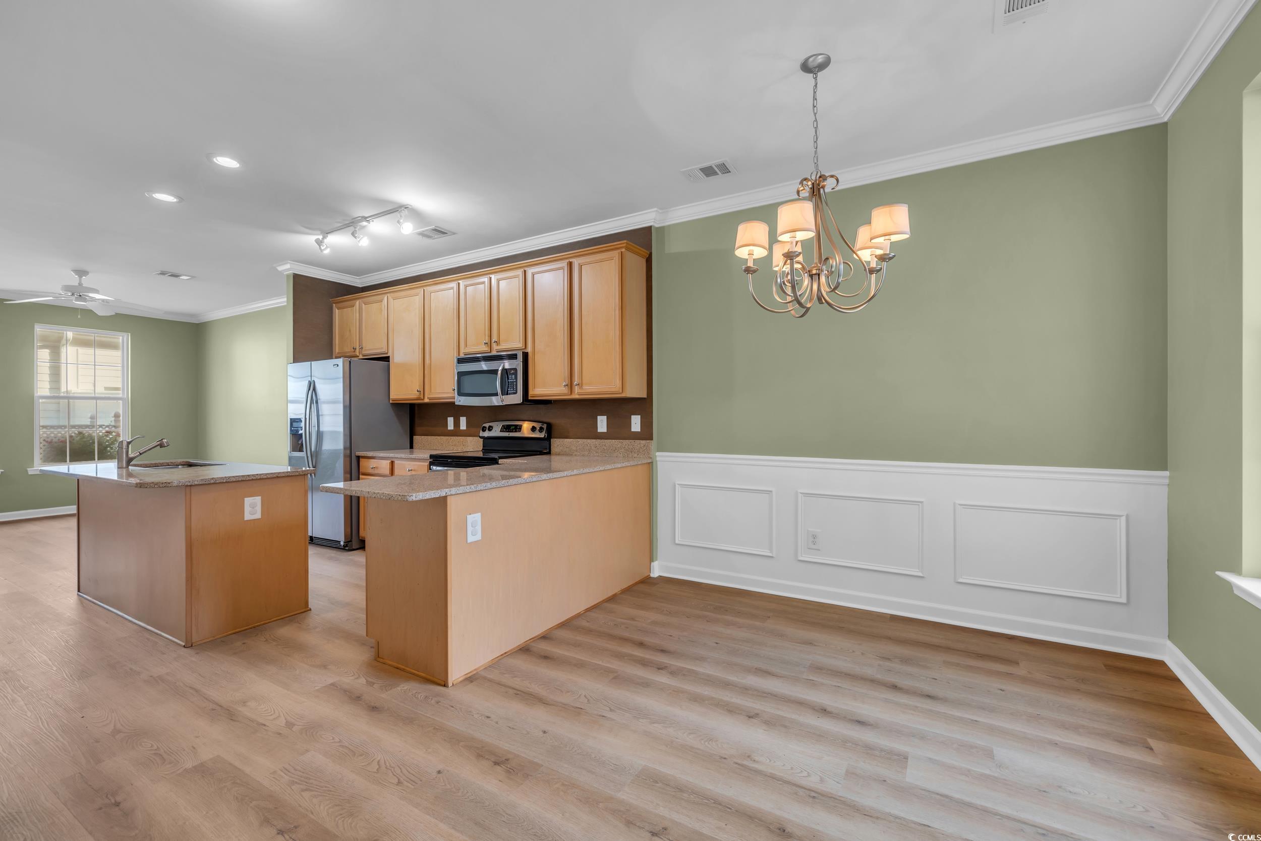 945 Rosencrans Lane, Unit B Myrtle Beach, SC 29577 - Photo 5 of 32 Kitchen featuring appliances with stainless steel finishes, ornamental molding, a chandelier, light wood-style floors, and a wainscoted wall