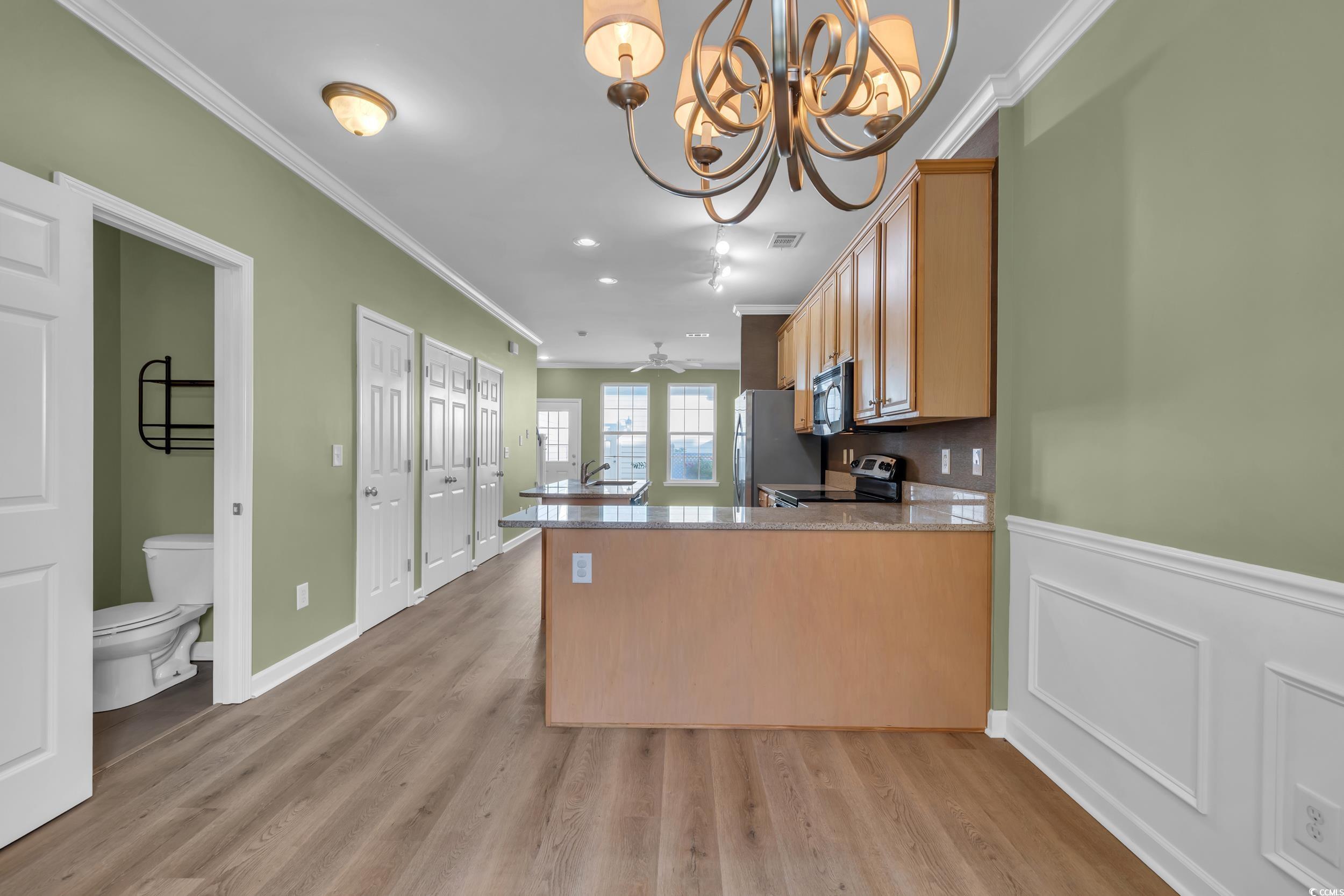 945 Rosencrans Lane, Unit B Myrtle Beach, SC 29577 - Photo 6 of 32 Kitchen with appliances with stainless steel finishes, crown molding, a chandelier, a peninsula, and light wood-style flooring