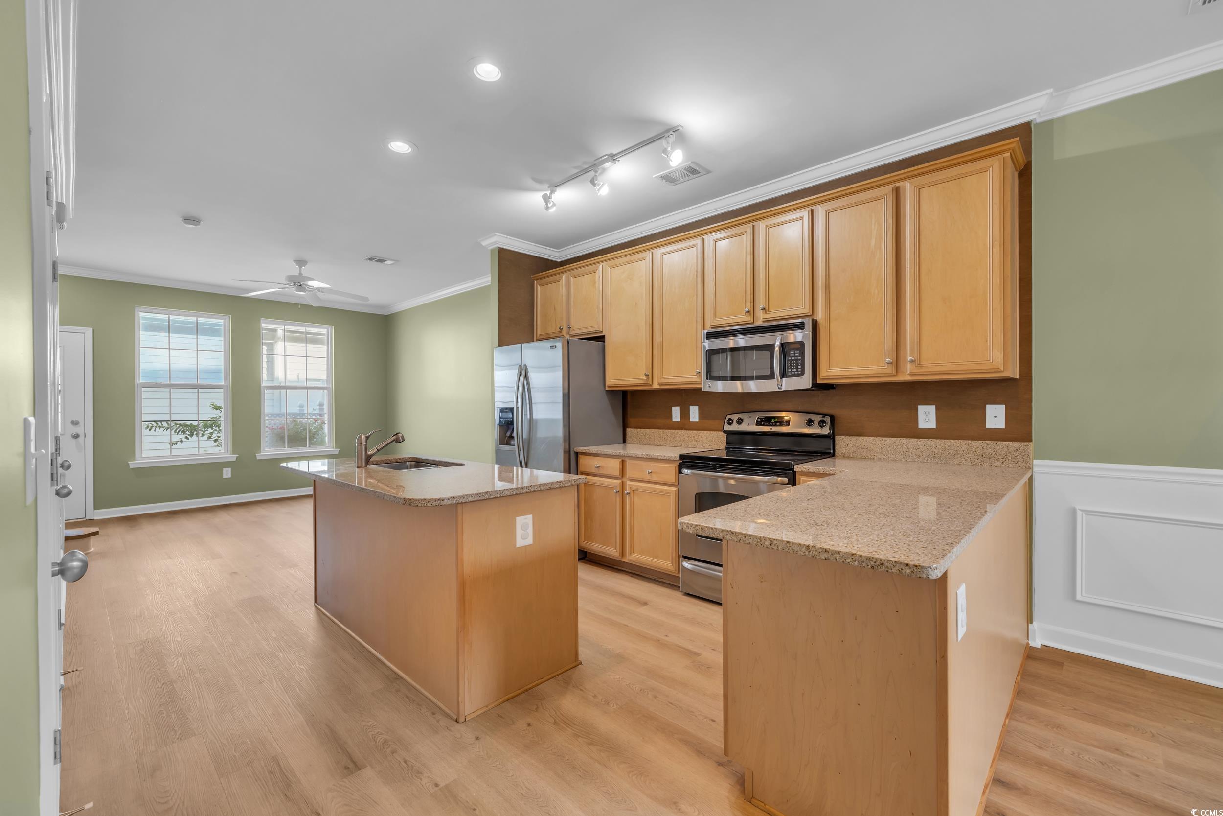 945 Rosencrans Lane, Unit B Myrtle Beach, SC 29577 - Photo 8 of 32 Kitchen with stainless steel appliances, crown molding, light wood-style floors, a ceiling fan, and a kitchen island with sink