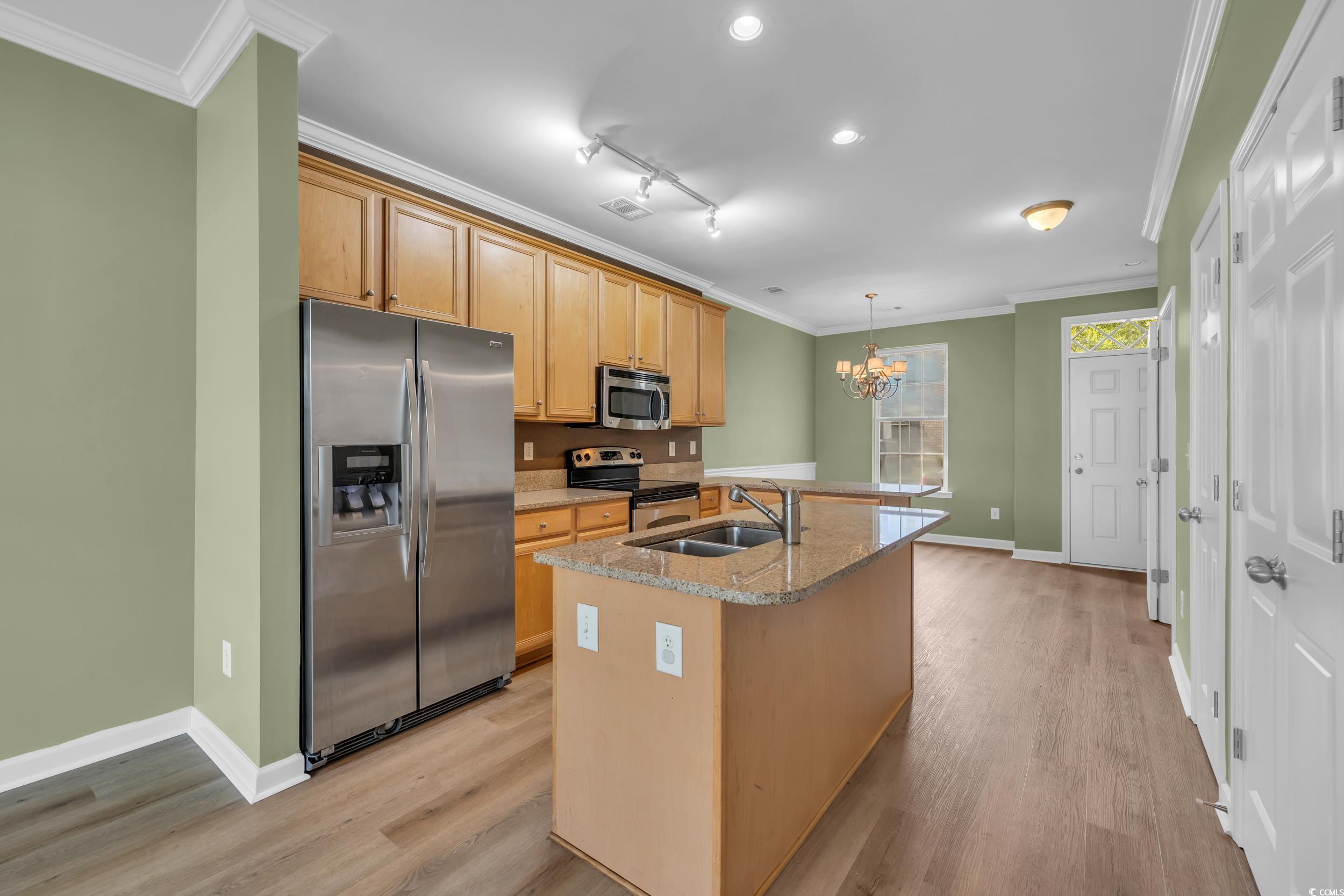 945 Rosencrans Lane, Unit B Myrtle Beach, SC 29577 - Photo 9 of 32 Kitchen featuring appliances with stainless steel finishes, a chandelier, a kitchen island with sink, crown molding, and light wood-style flooring