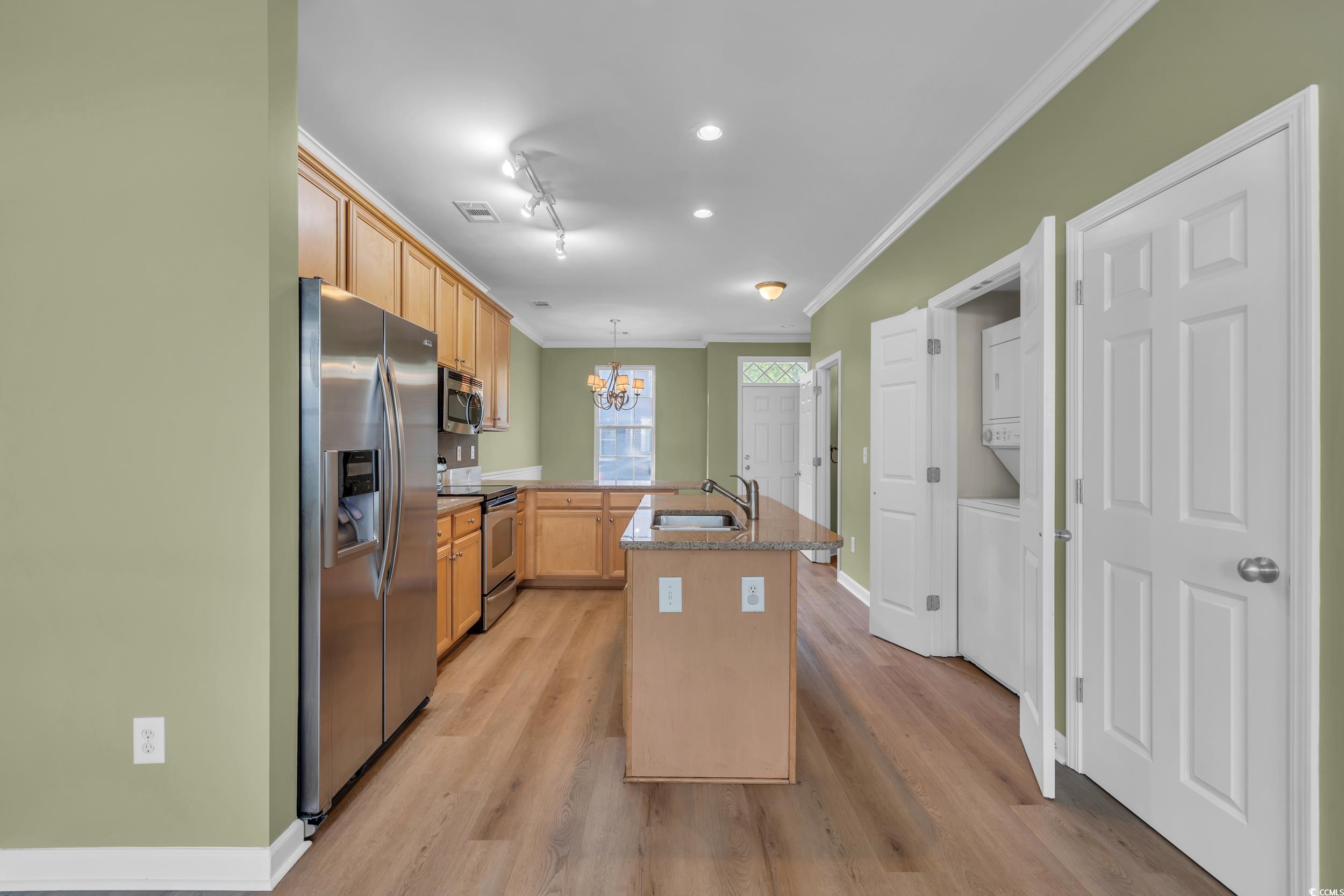 945 Rosencrans Lane, Unit B Myrtle Beach, SC 29577 - Photo 10 of 32 Kitchen with stainless steel appliances, stacked washer / drying machine, ornamental molding, a peninsula, and a chandelier