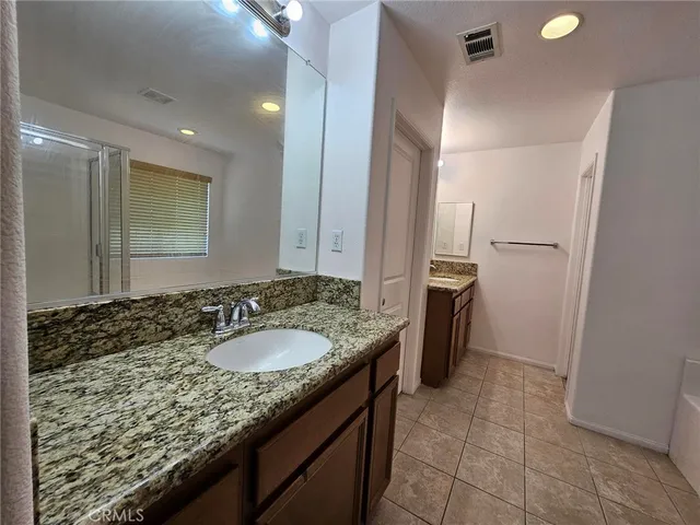 a bathroom with a granite countertop sink a mirror and a shower
