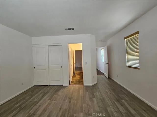 a view of an empty room with wooden floor and closet