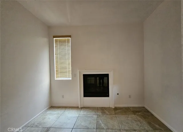 a view of an empty room with a window and fireplace